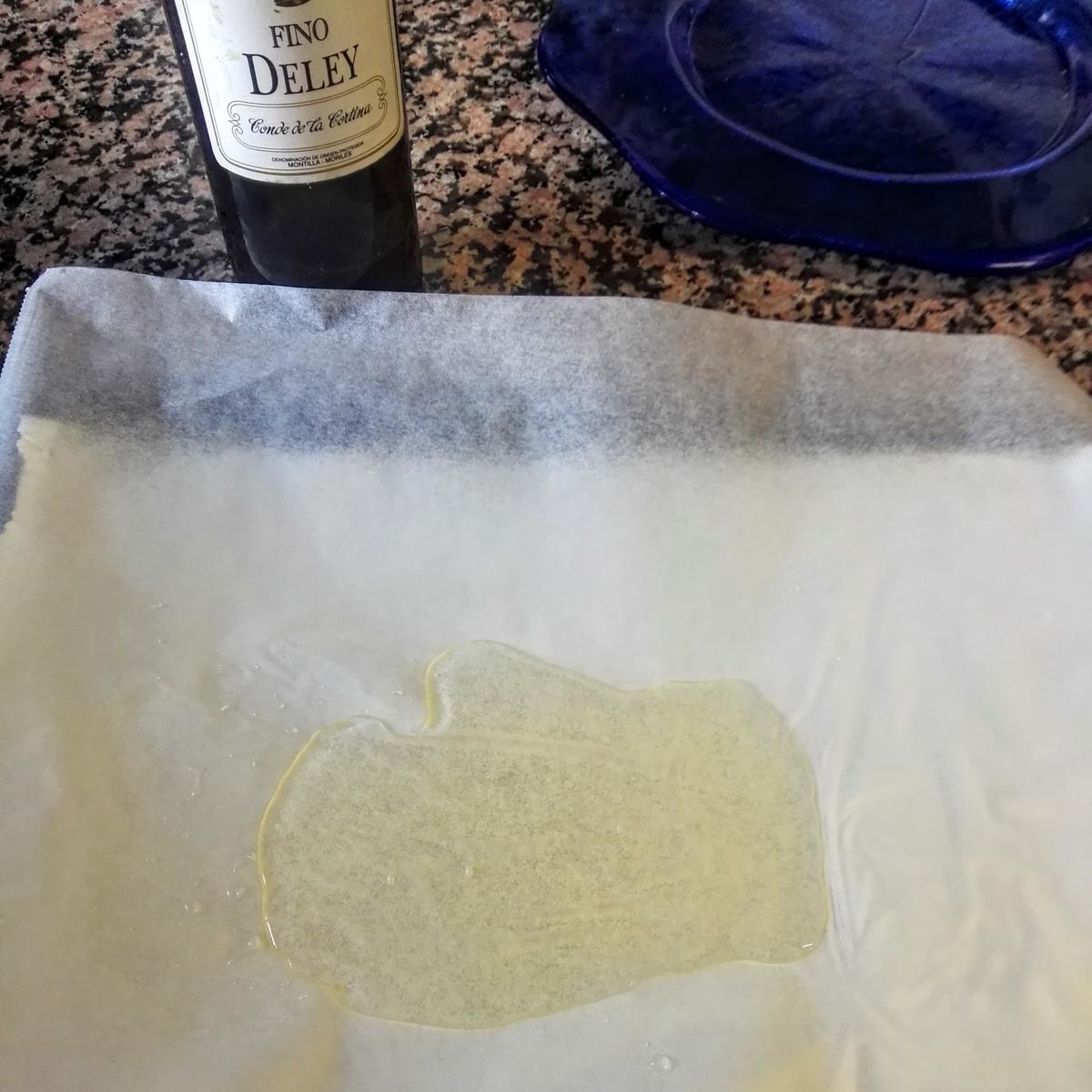 Poniendo vino blanco de cocina en la bandeja del horno