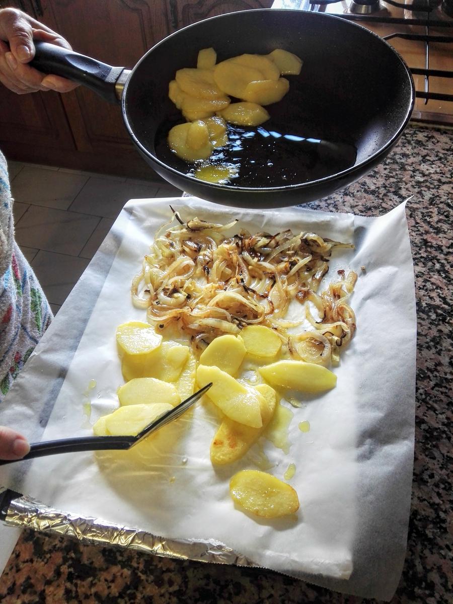 Colocando patatas y cebolla en la fuente del horno