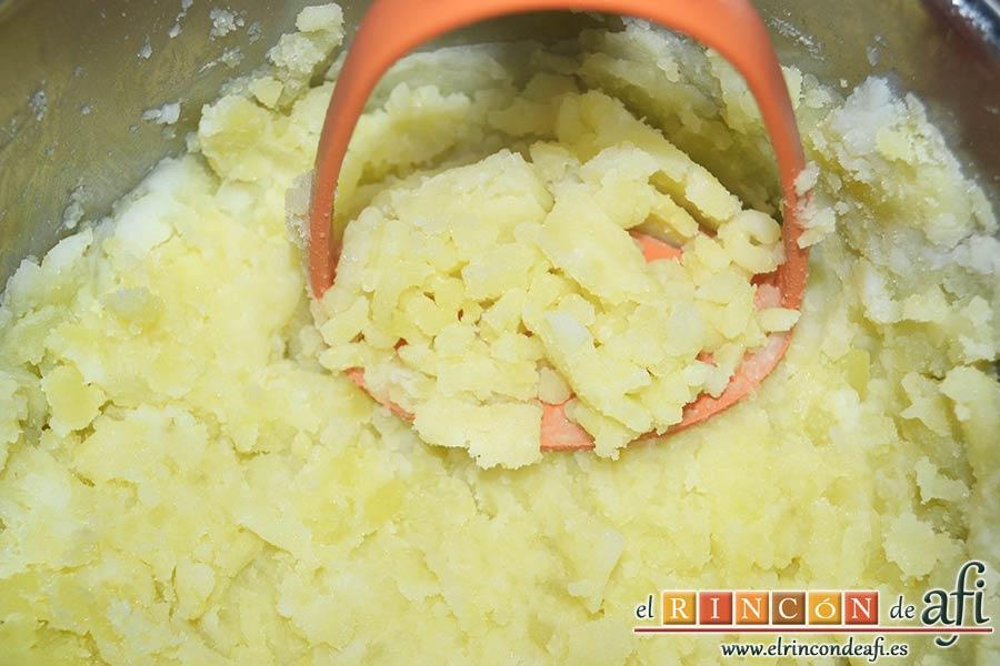 Pastel de bacalao, escurrir las papas y machacarlas