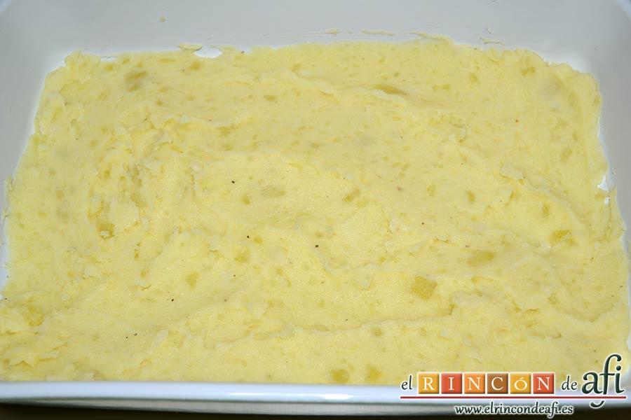Pastel de bacalao, hacer una cama de puré de papas en una fuente para horno