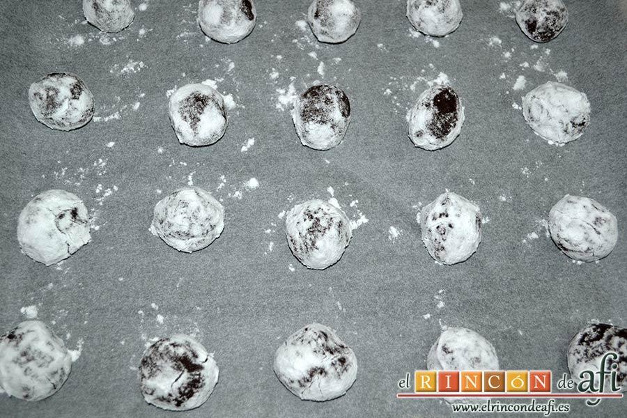 Galletas de Navidad de chocolate y avellanas, cortar la masa en porciones, formar bolitas, pasar por azúcar glass y disponer por bandeja de horno forrada