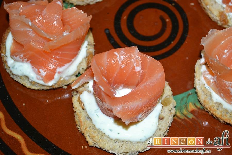 Rosas de salmón, poner una cucharada de crema sobre cada círculo y formar una rosa con salmón enrollando una loncha