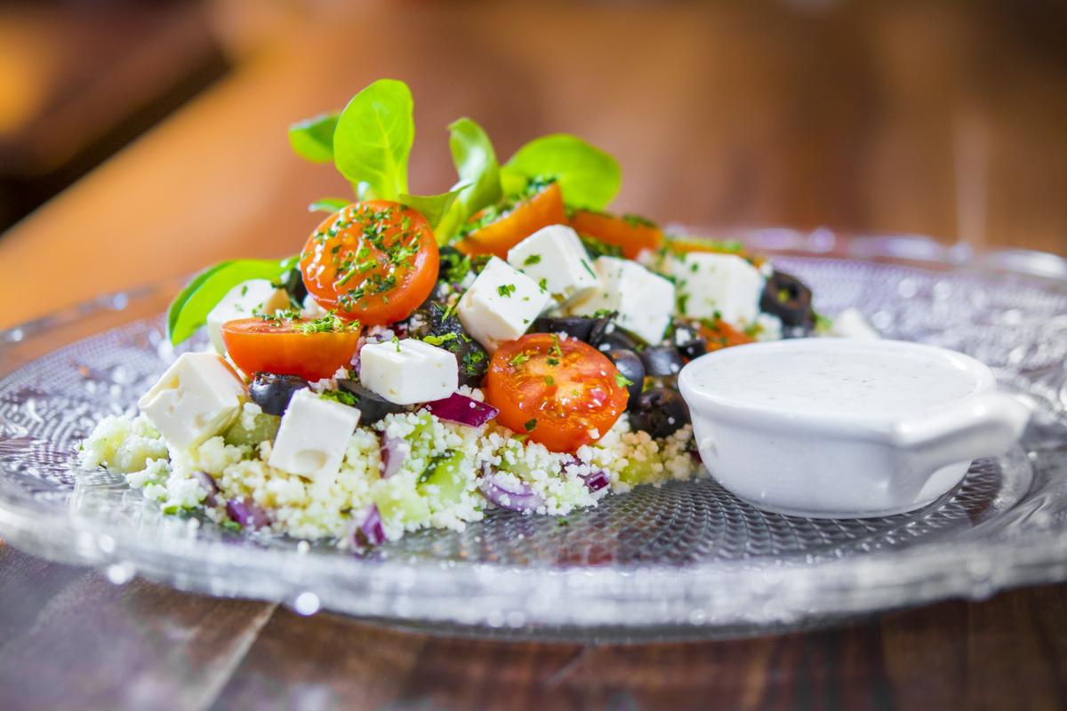 Tabulé con semola de trigo, queso feta, tomates cherry, cebolla roja, aceitunas negras y salsa de yogur y menta