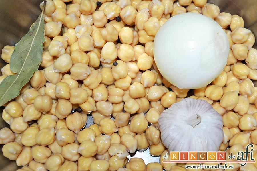 Bacalao a la calesera, en una olla a presión pondremos los garbanzos escurridos con el laurel, la cebolla pelada, la cabeza de ajos entera y los granos de pimienta negra