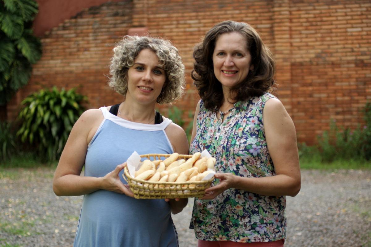 dos señoras paradas cib una bandeja de chipas