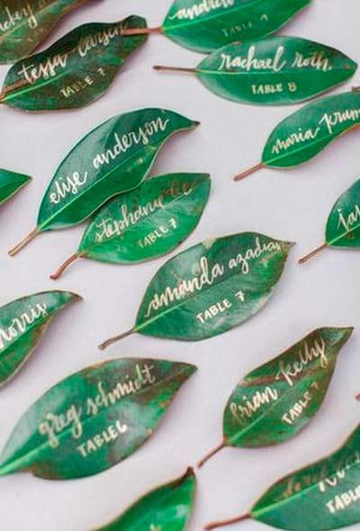 hojas de árbol decoradas y barnizadas para utilizar como tarjetas marcasitios para el banquete de una boda
