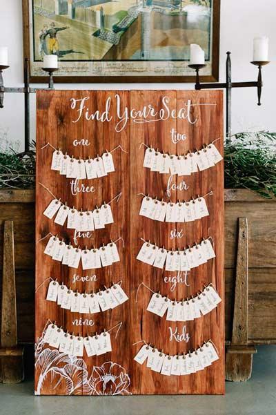 idea de decoración para boda rústica con el mural de invitados de madera con etiquetas