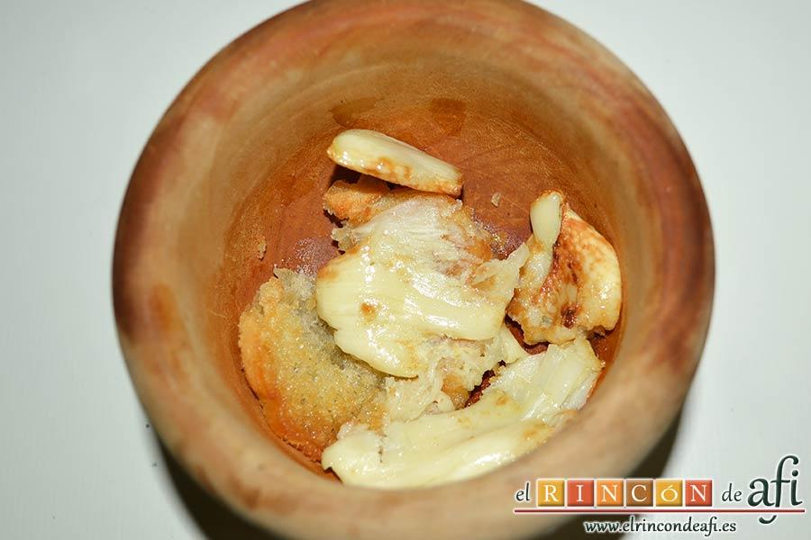 Sopa de pan con majada de almendras, meter en un mortero los ajos y una rebanada de pan y machacar