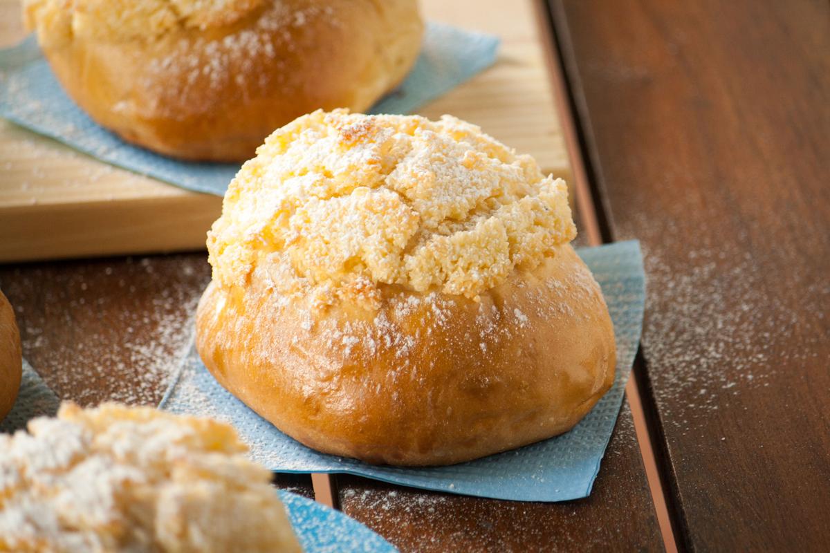 Pão de Deus (pan portugués) sobre servilleta celeste en una mesa de madera