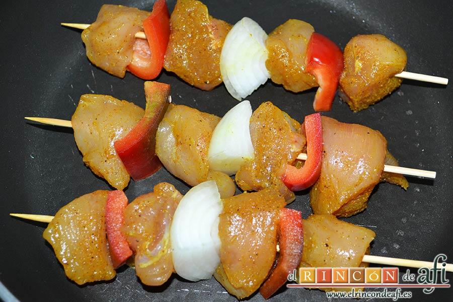 Brochetas de pechuga de pollo marinadas al curry con cebollas y pimientos, dorar sin nada de aceite