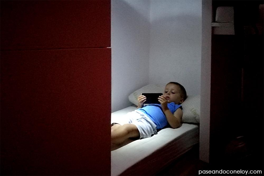 niño pequeño tumbado en la cama viendo dibujos