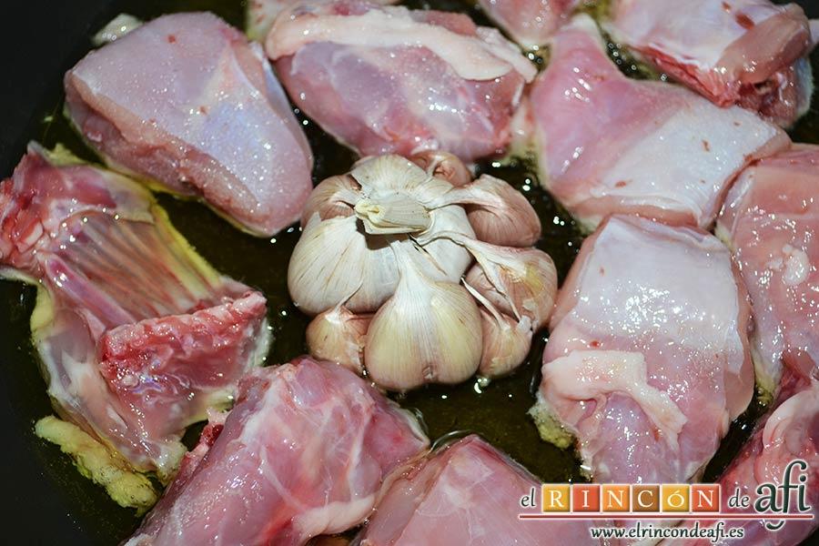 Conejo estilo Afi, en una sartén con aceite de oliva ponemos en el centro la cabeza de ajos y vamos dorando el conejo