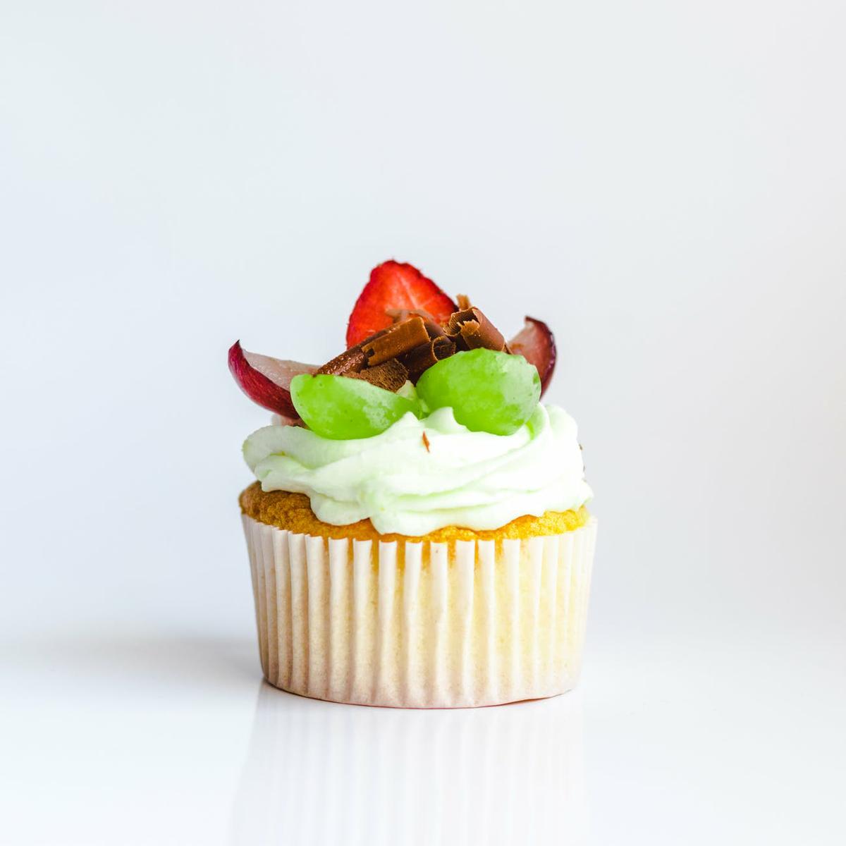 white and yellow cupcake with fruit toppings
