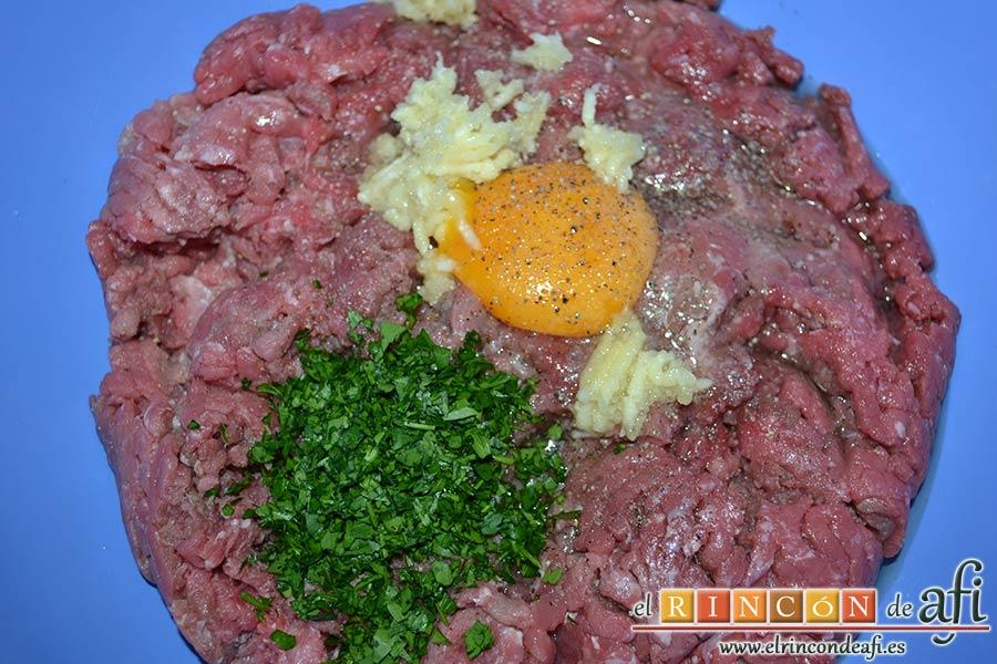 Albóndigas con salsa de cebollas, en un bol amplio colocamos las carnes picadas y le añadimos el huevo, los dientes de ajo machacados, la sal y la pimienta, y el manojito de perejil fresco picado