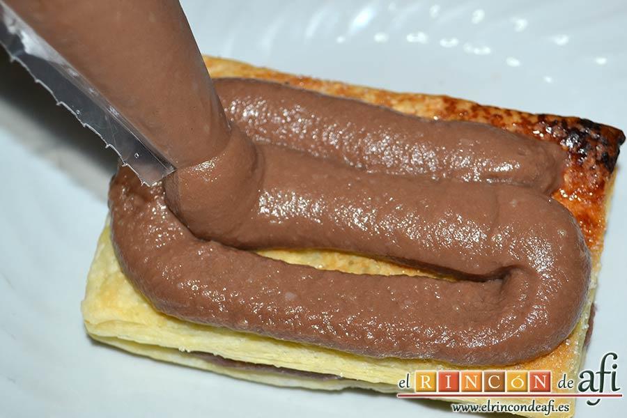 Milhojas de hojaldre con chocolate, poner encima un trozo de hojaldre y repetir la operación hasta que se acabe tanto el hojaldre como la crema