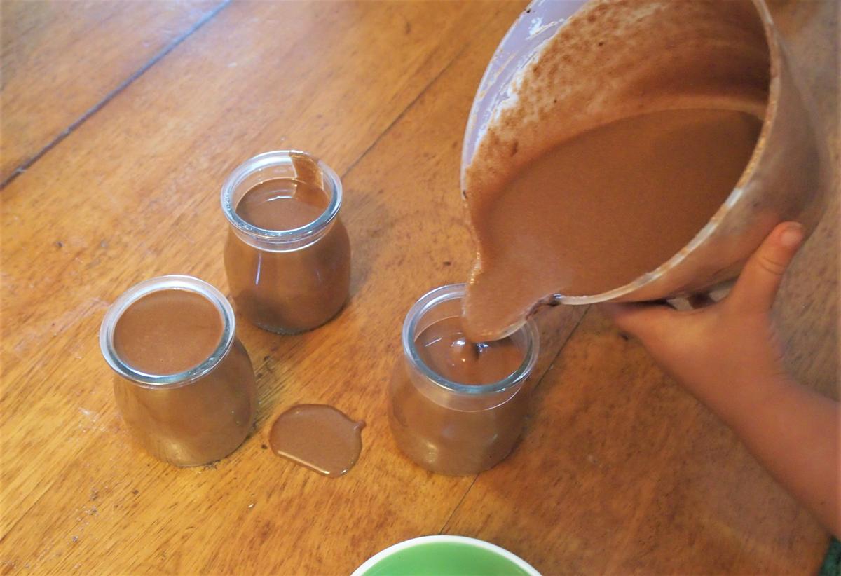 Niño sirviendo el preparado de la mouse en vasos, un poco se ha caido