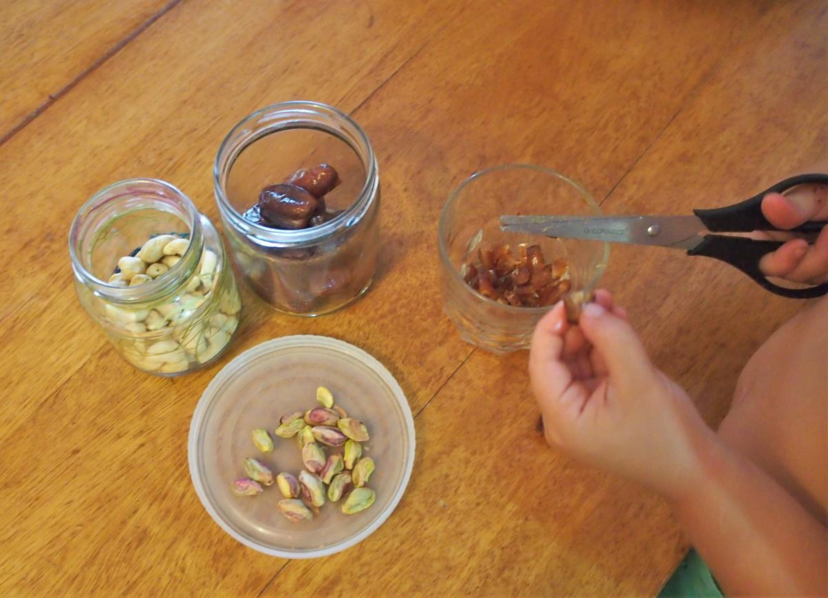 Manos de niño corando datiles con las tijeras