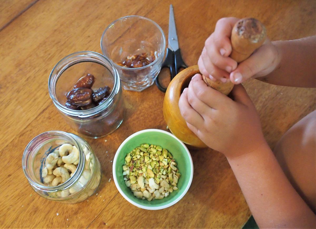 Manos de niños con mortero picando frutos secos