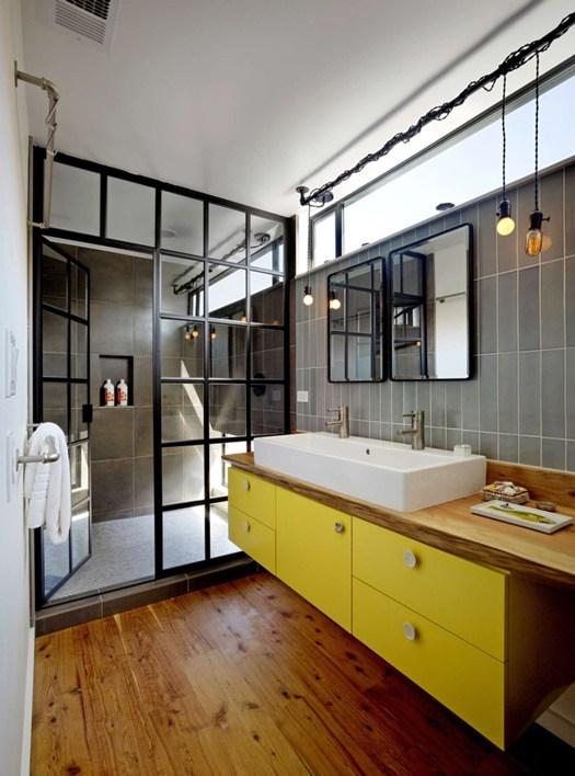 Cuarto de baño de estilo industrial con detalles en amarillo y madera.