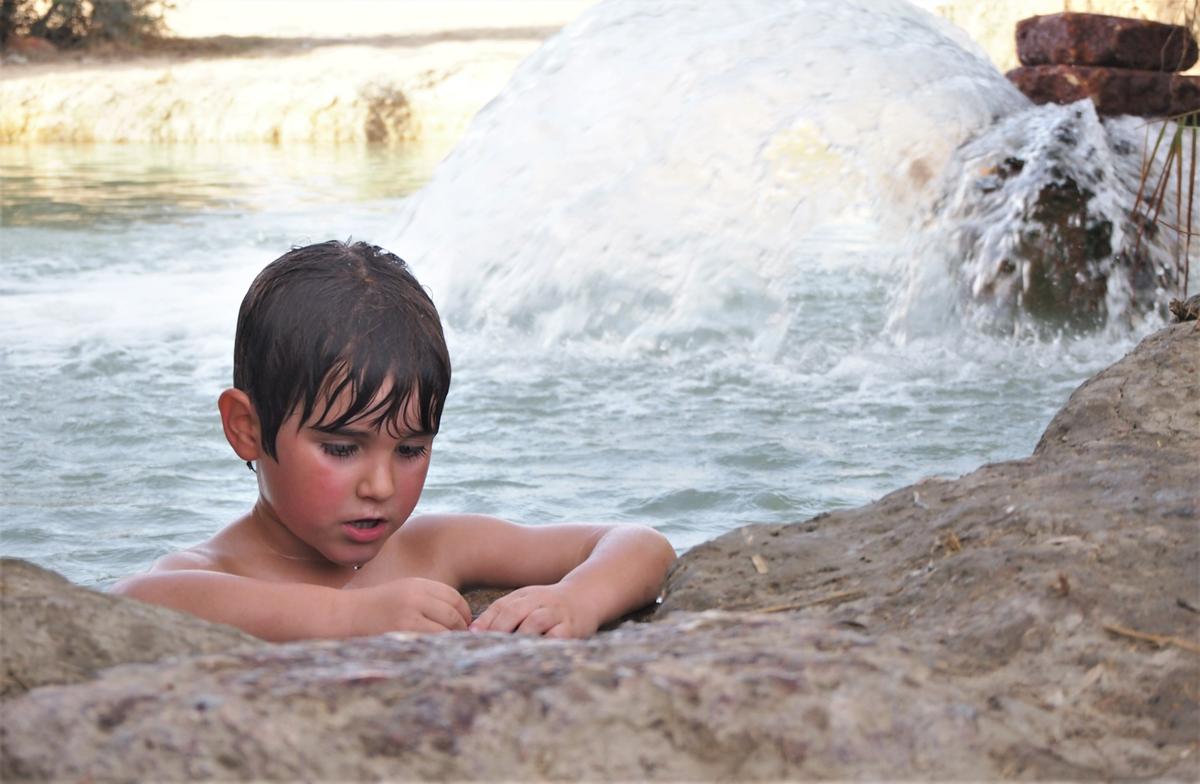 Eric muy concentrado jugando con piedrecitas en la poza de arriba, termas de Santa Fe, Granada