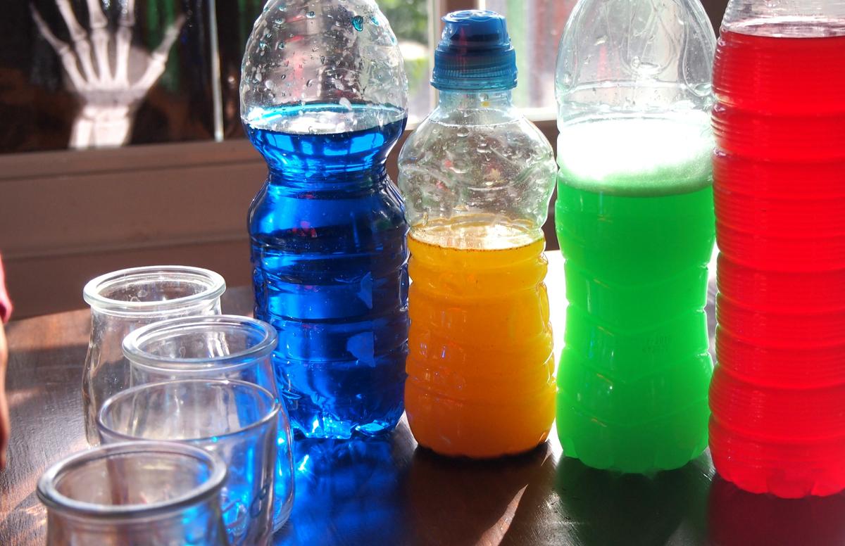 Juego de luz en la ventana. Botellas con agua de colores. Los colores se ven muy vivos. 