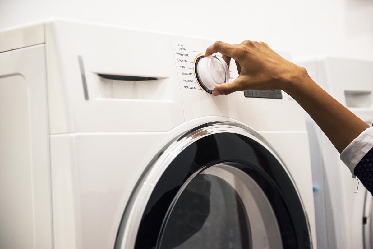 person using white front-load washing machine