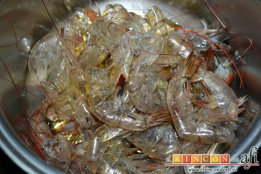 Risotto con langostinos y calabacines, pelarlos, desvenarlos y poner las pieles y cabezas en un caldero con aceite de oliva