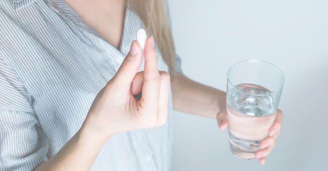 mujer tomando una pastilla de algun complemento alimenticio
