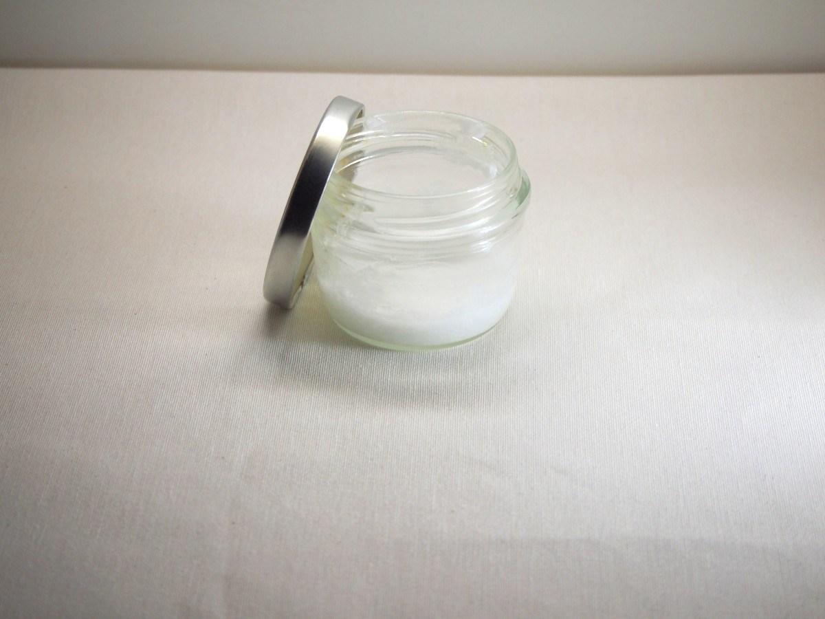 Bote de cristal con desodorante casero natural hecho sobre fondo blanco 