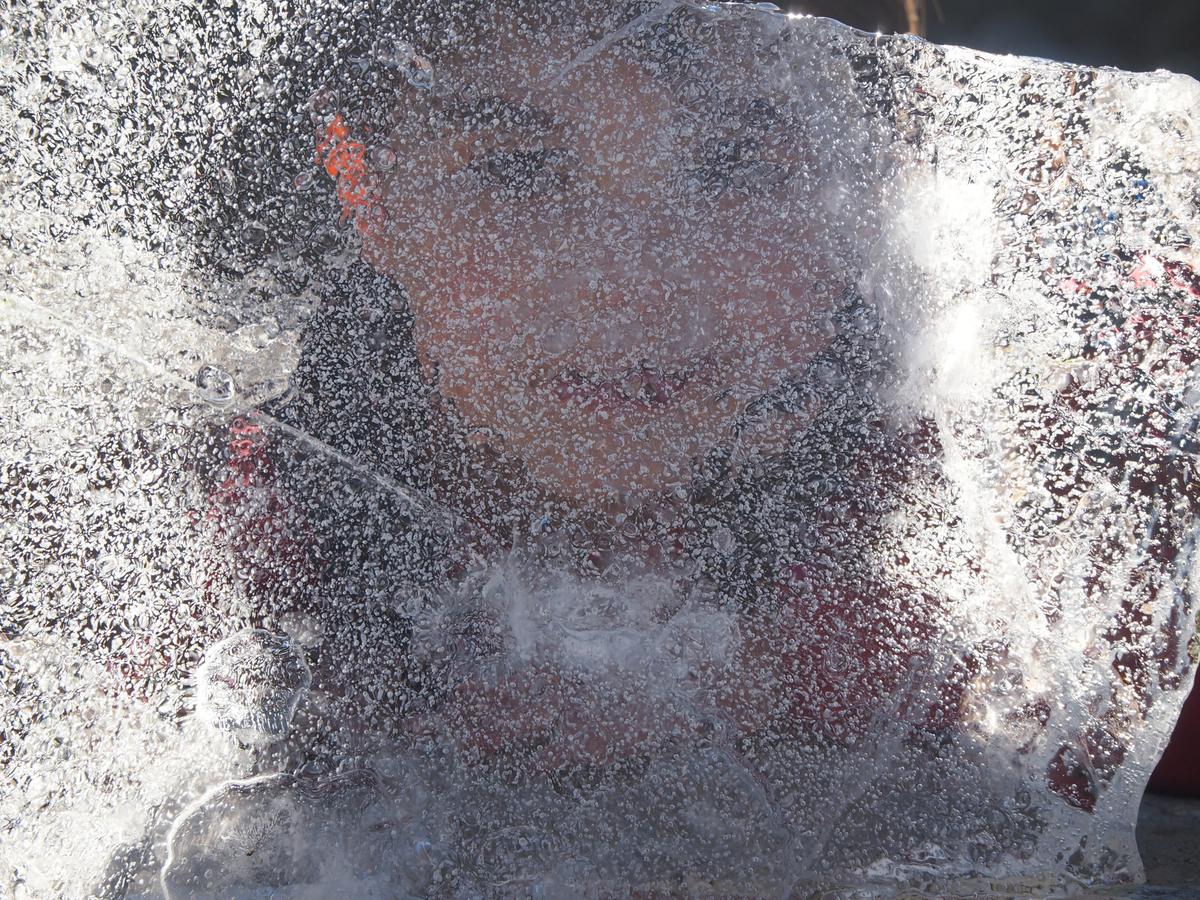 Jugar con hielo de los charcos, retrato de mi sobrino a traves del hielo.