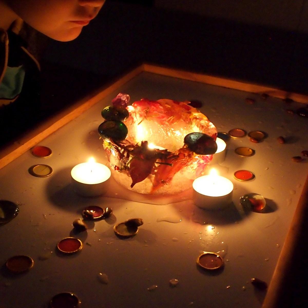 Bol de hielo con flores y velas en en centro y alrededor. El efecto visual es muy bello y relajante