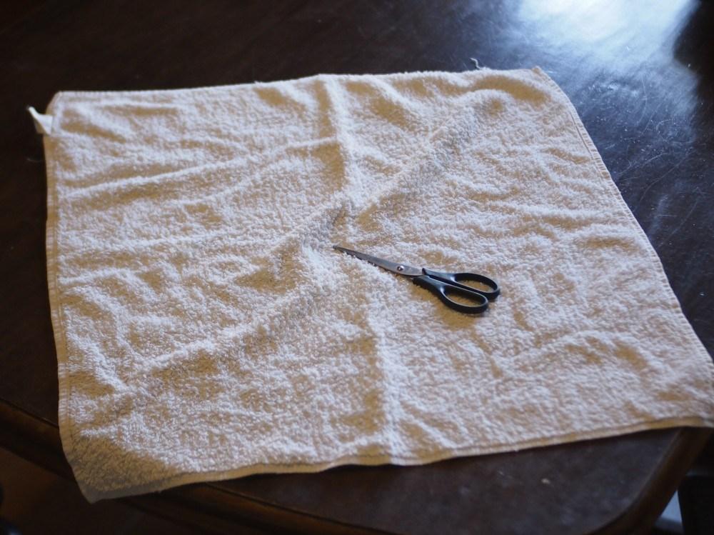 Foto de una toalla y unas tijeras para hacer toallitas lavables en casa