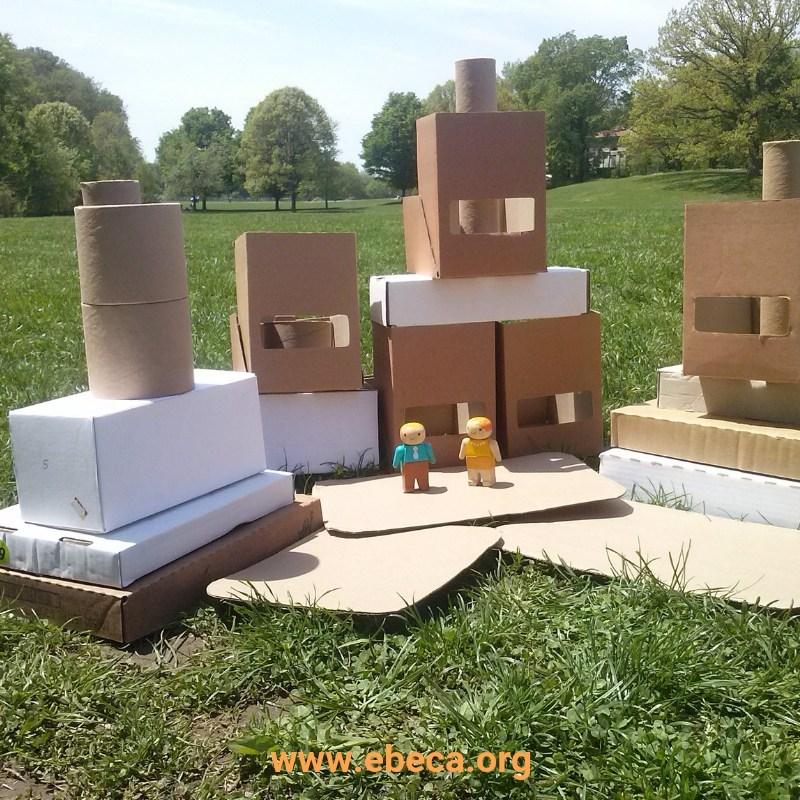 Construcciones con cartón y muercos en una explanada de césped