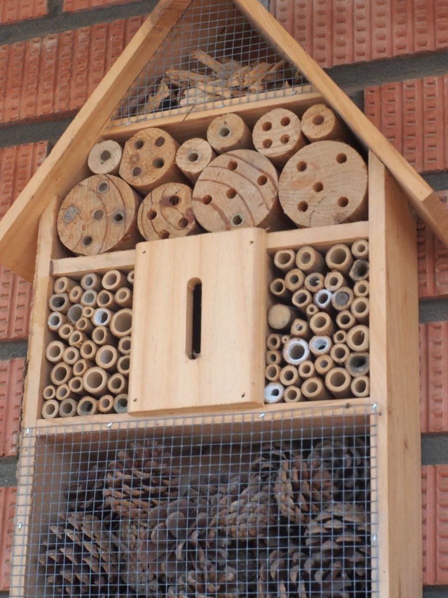 Hotel de insectos comprado donde se ven las cañas y las maderas con agujeros asi como piñas y maderas