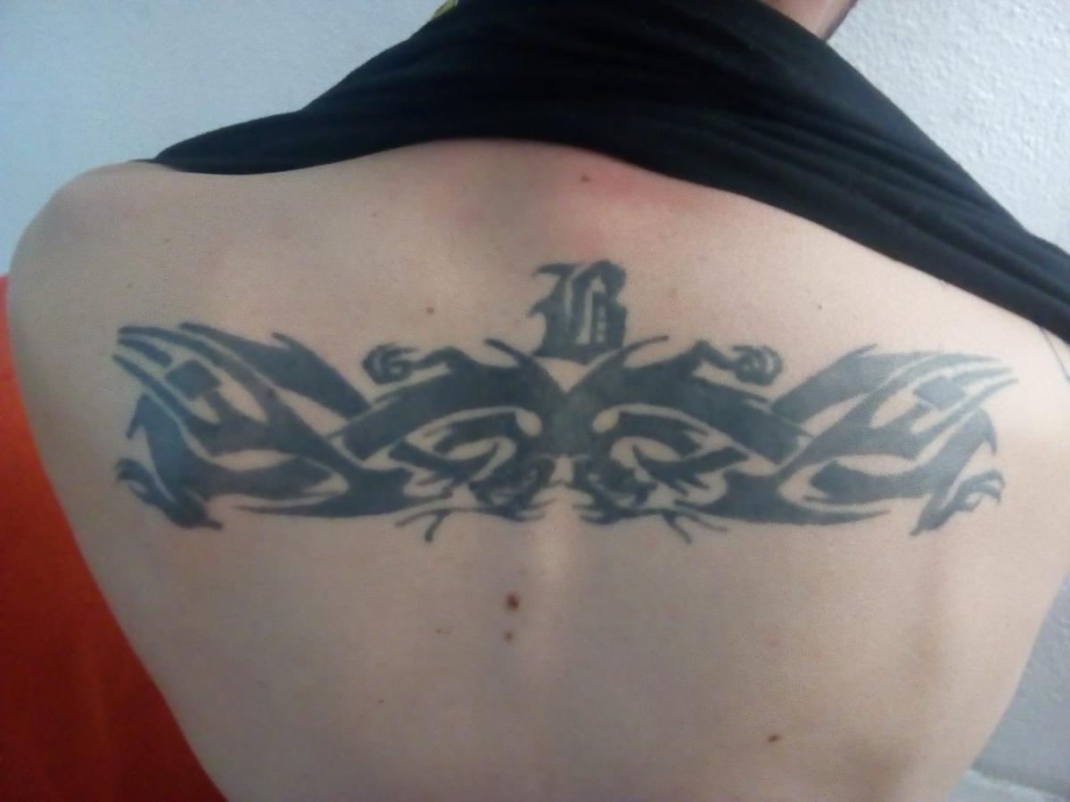 Tatuaje tribal en la espalda con inicial de una madre