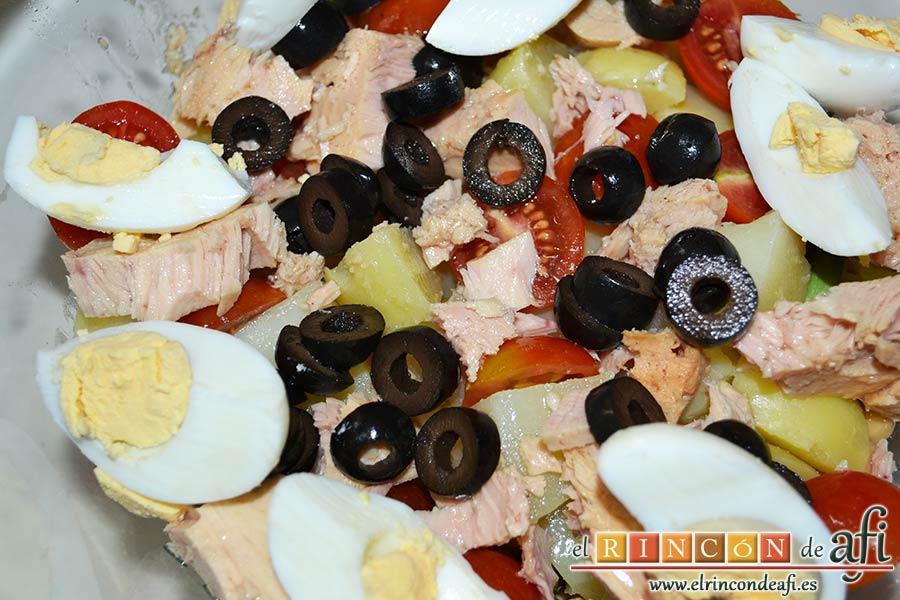 Ensalada de garbanzos, papas, tomates, atún y huevos, añadir los huevos pelados y partidos en cuartos, así como las rodajas de aceituna