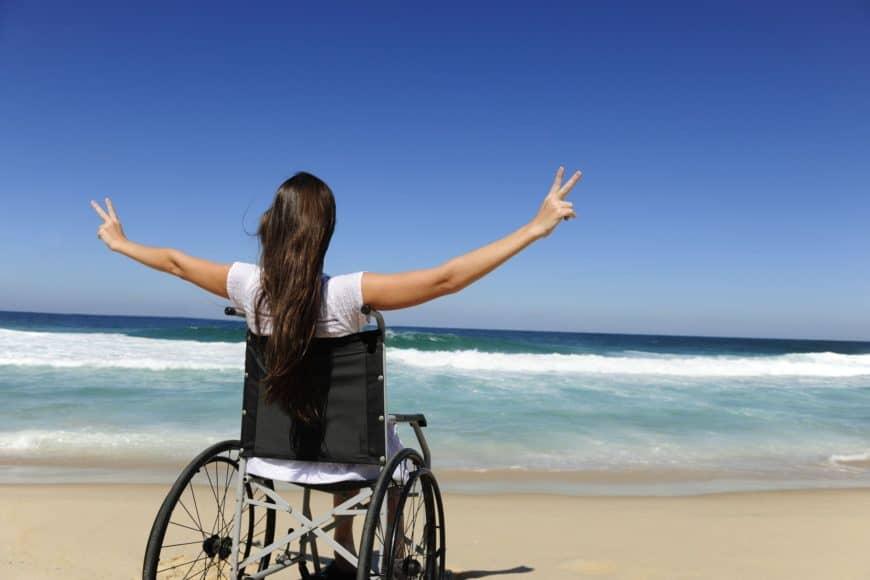 Mujer en silla de ruedas en playa con turismo accesible e incluyente