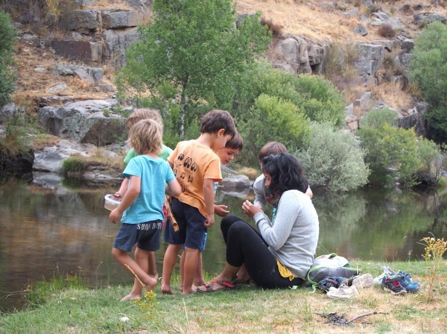 Niños observando bichos en el rio