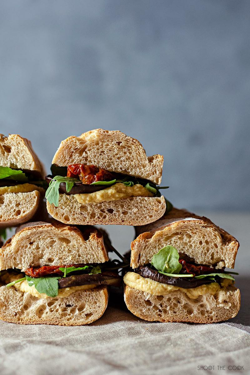 Bocadillos saludables de hummus, berenjena, tomate seco y rúcula
