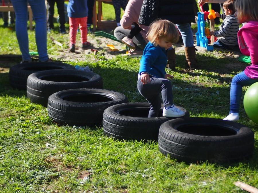 Mini yincana hecha con neumaticos y un niños pequeño pasando por encima
