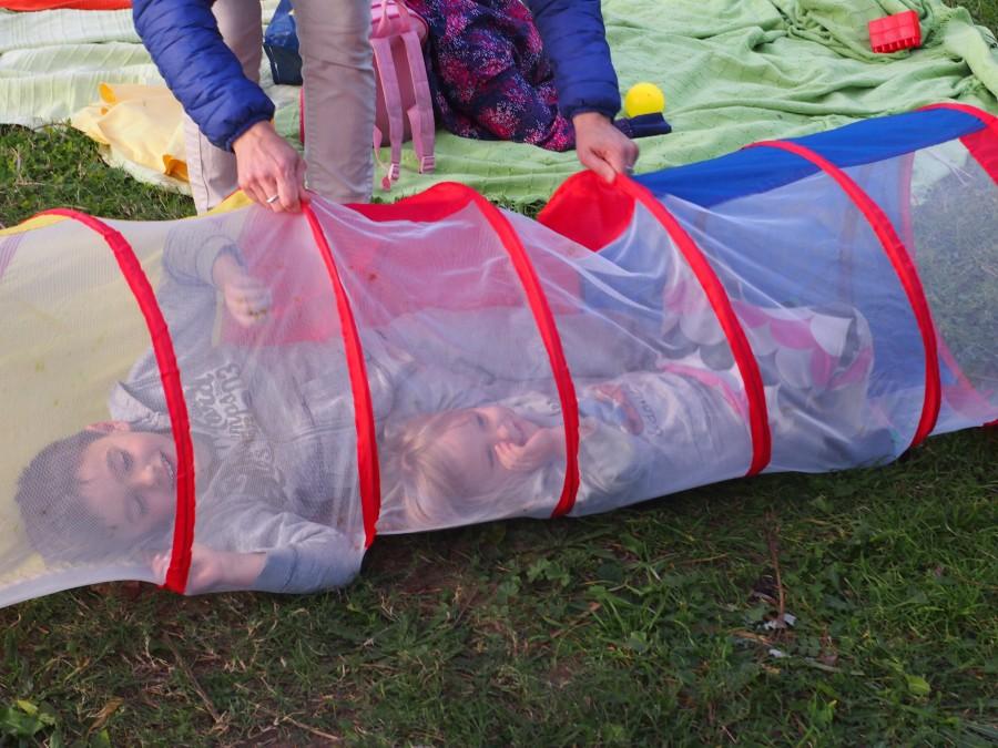 Niños jugando en un tubo transparente con una madre. Una de las normas del grupo de juego es jugar con tus hij@s