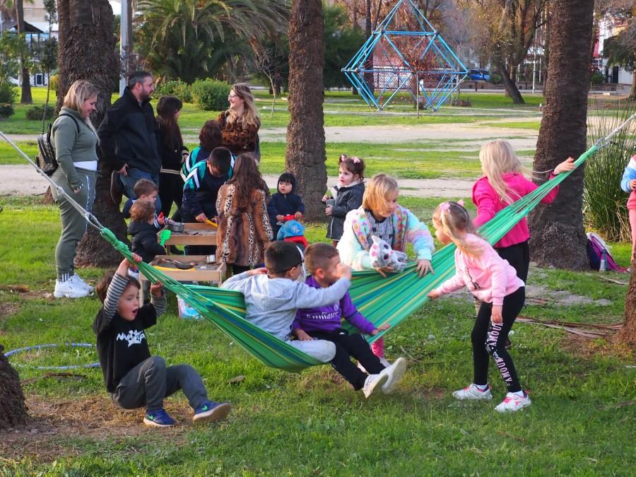 Niños y niñas jugando en una hamaca. Familias detrás observando, una de las normas es acompañar