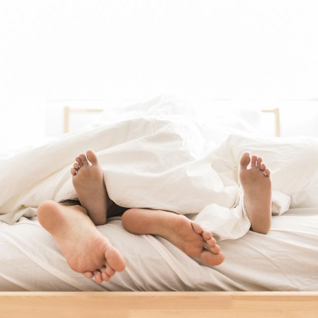 Pareja, acostado, descalzo, en cama Foto gratis