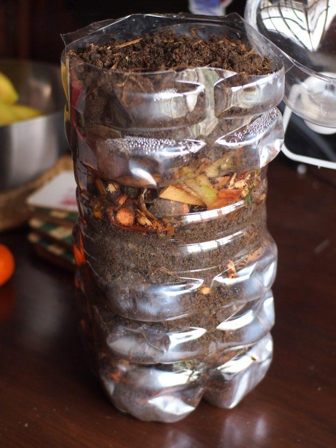 Bidón lleno de capas de tierra y desechos de cocina para compostar en tu terraza