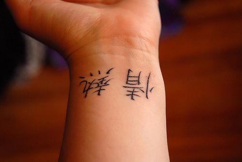 Tatuaje Kanjis de tinta negra en la muñeca