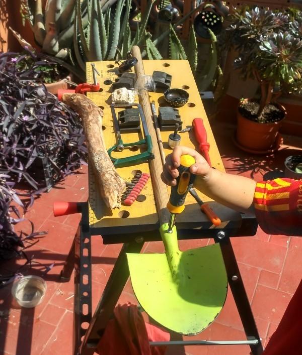 Restauración con niños, arreglando su pala de madera y metal en la terraza en el banco de trabajo