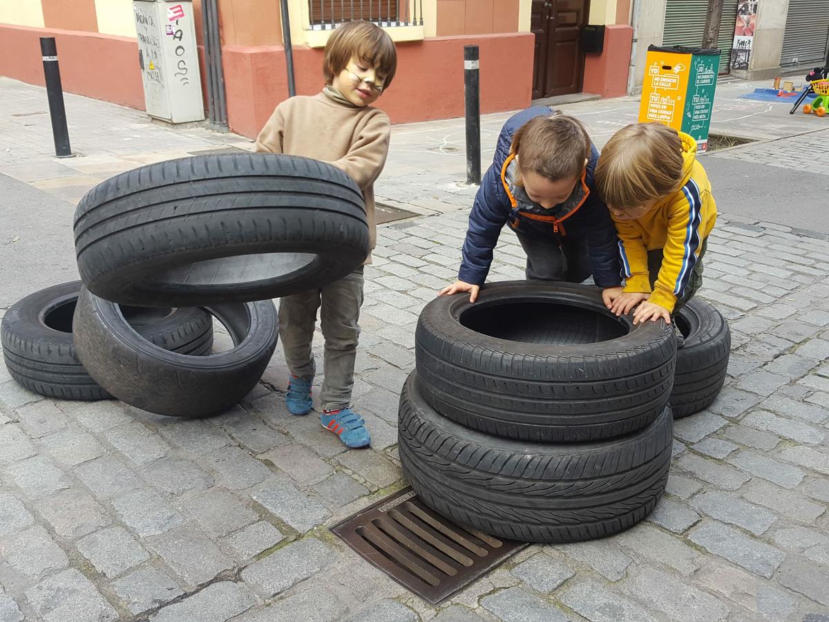 Niños jugando con neumaticos en la calle