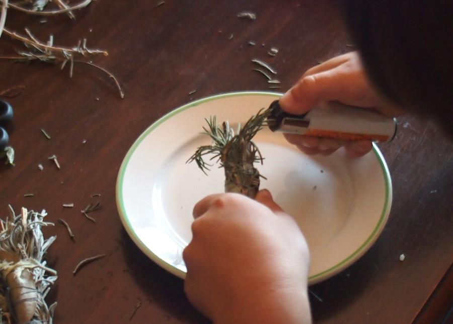 Manos de niño encendiendo un atado de hierbas para sahumerios