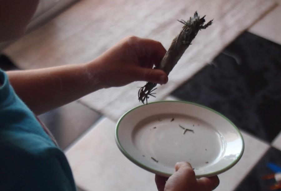 Manos de niños sujetando un atillo de hierbas prendido