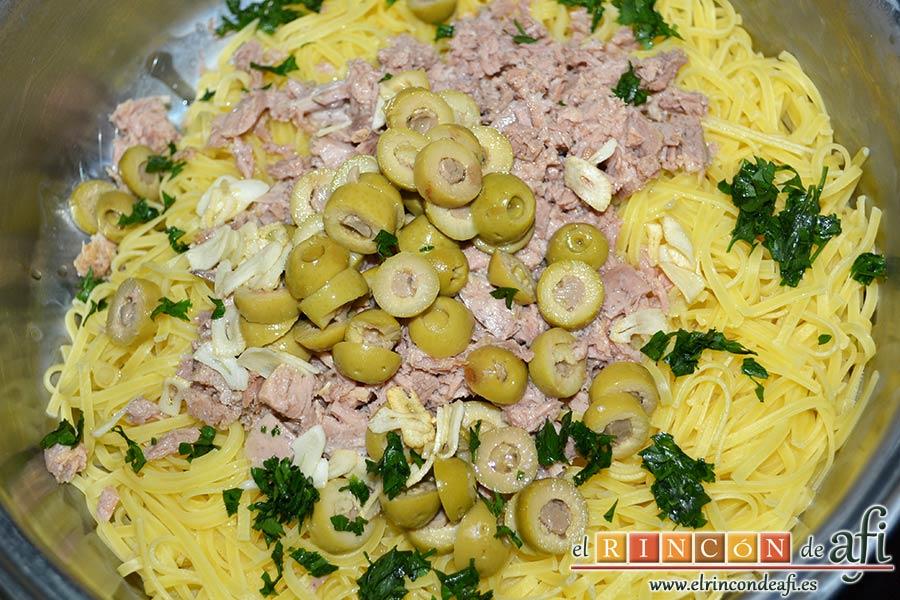 Espaguetis con atún y aceitunas, verter por encima el aceite con los ajos y el perejil picado